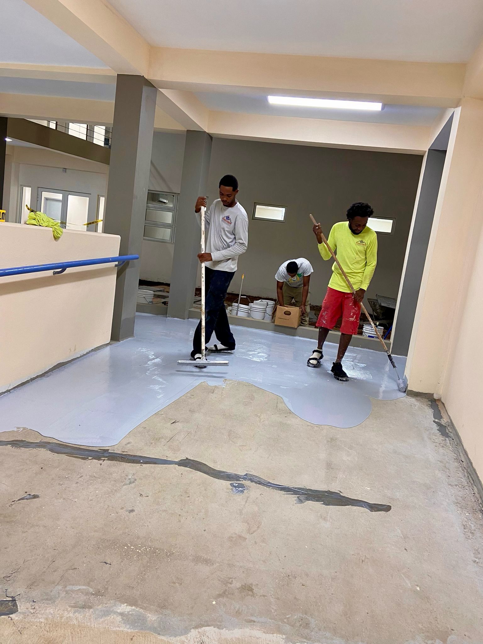 Premier Roofing crew installing commercial-grade epoxy flooring in a Caribbean commercial space